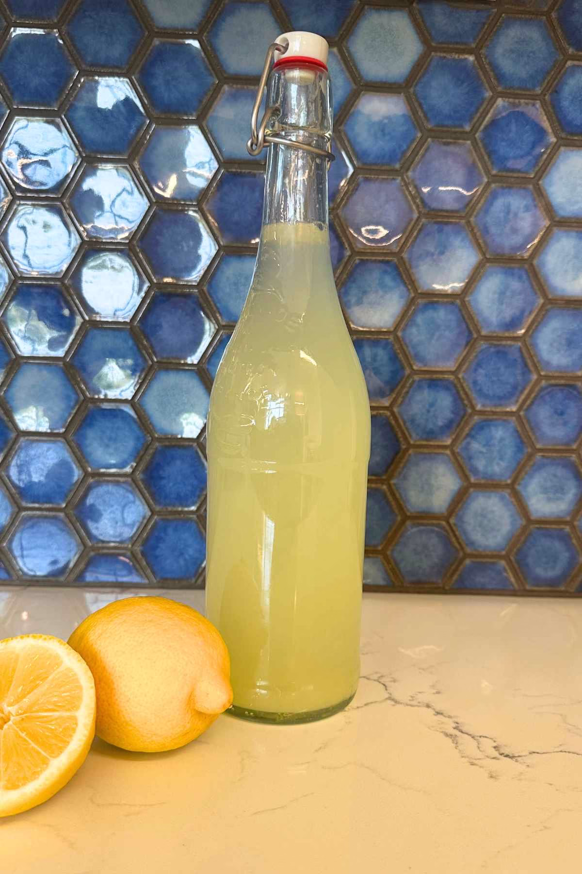 A swing top bottle filled with lemonade, and lemons in the foreground